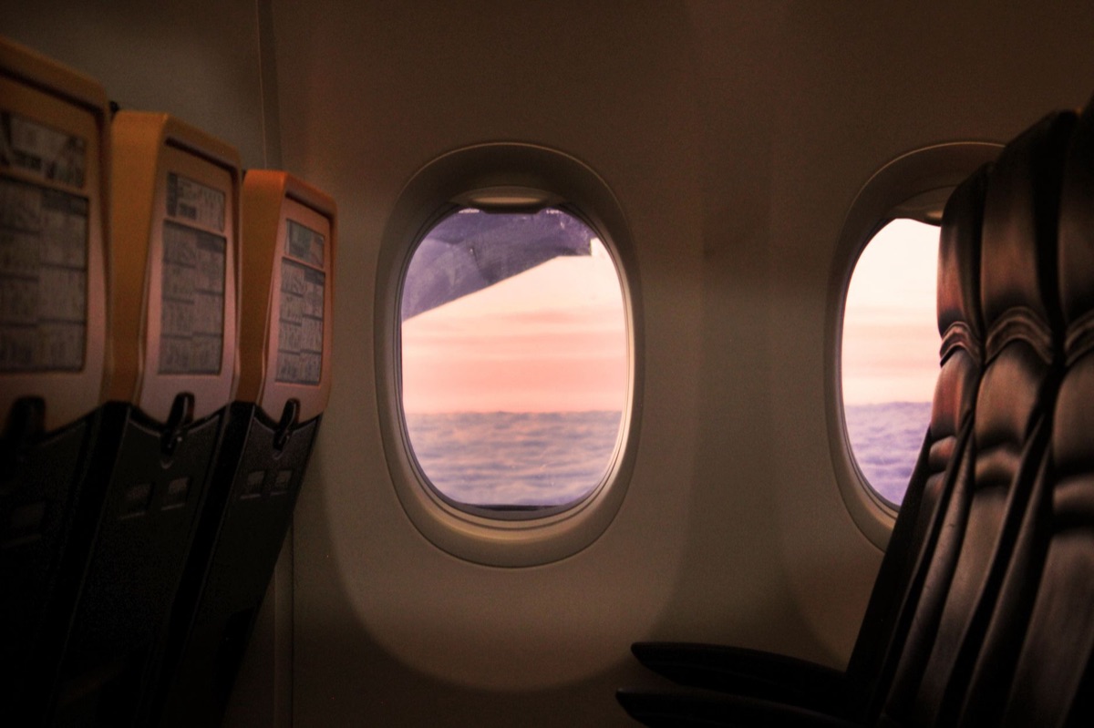 Airplane window with tropical sunset
