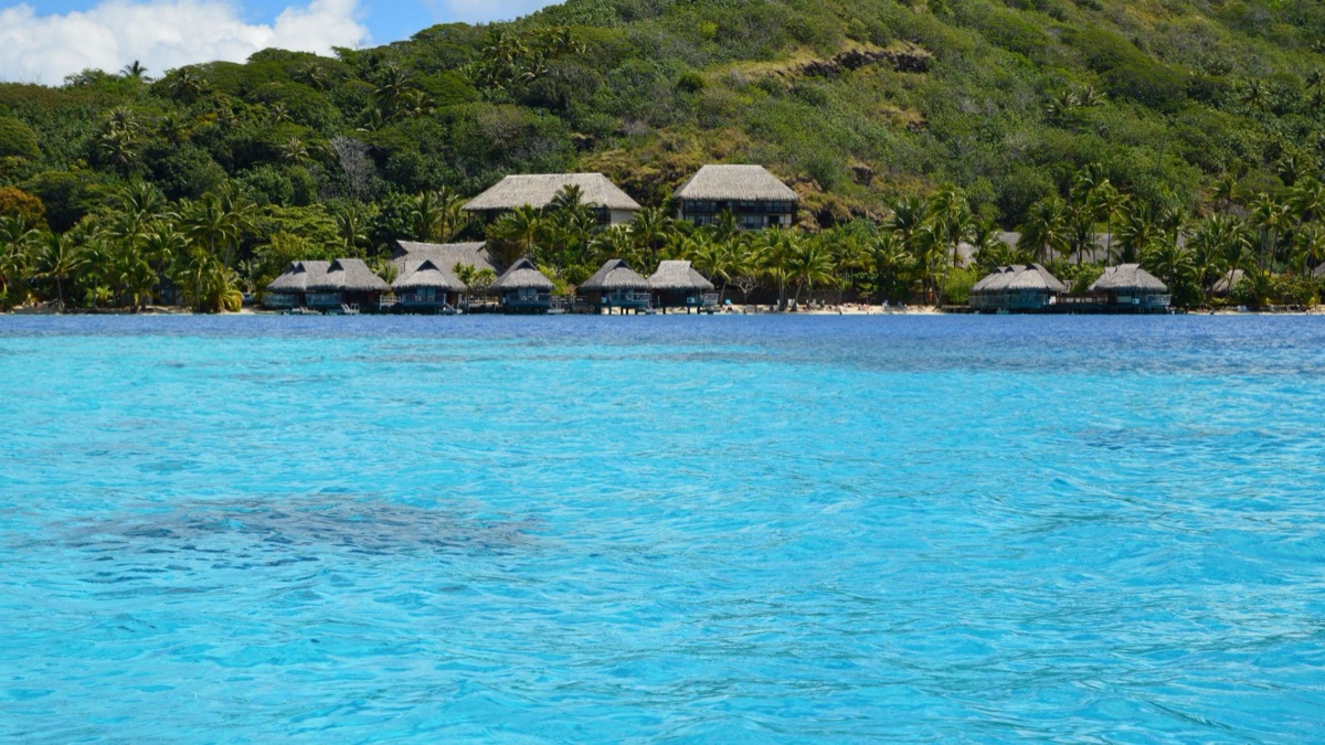 Panorama dell'isola di Tahiti, mare blu, cielo azzurro, montagne lontane