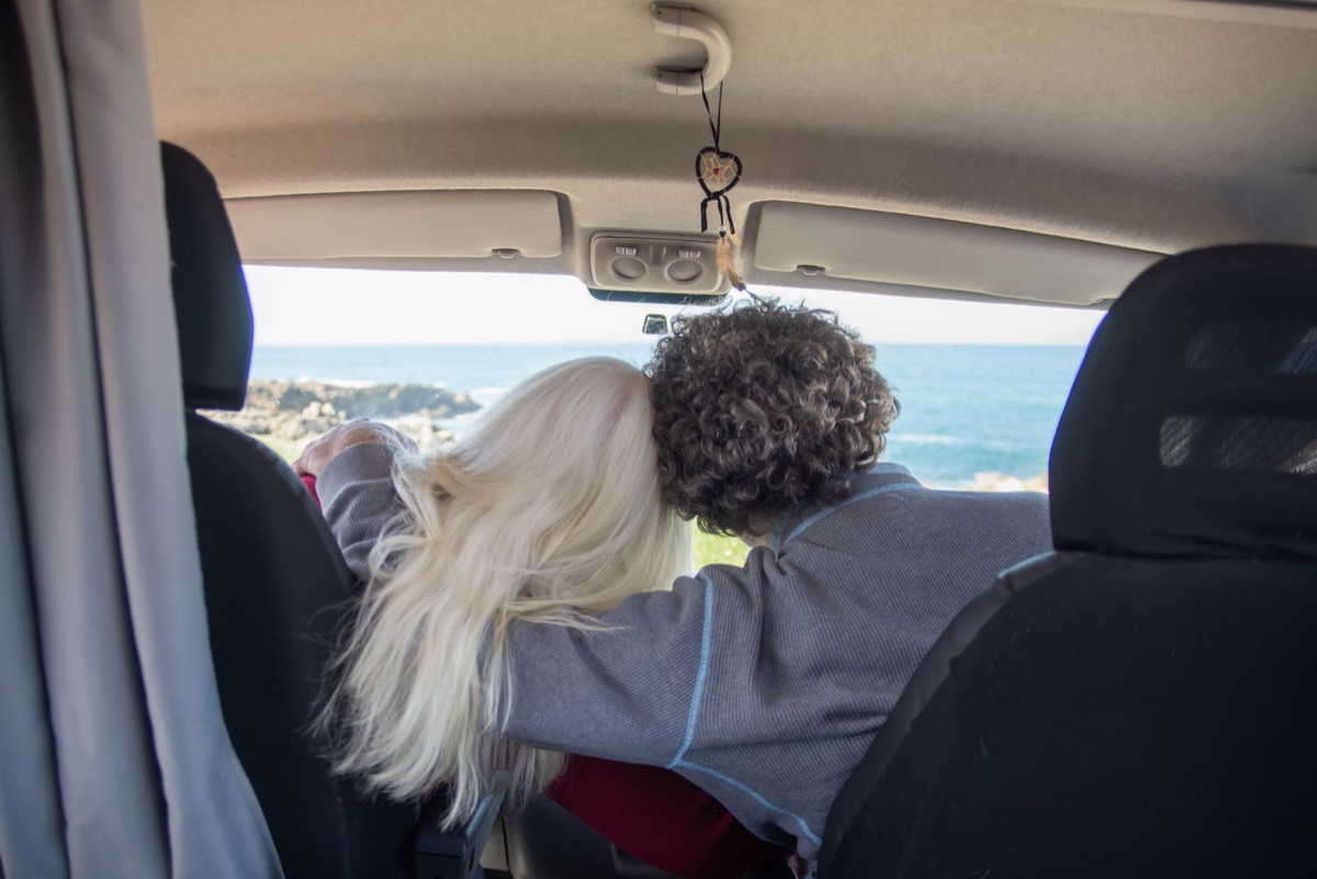 Couple dans une voiture louée regardant en arrière