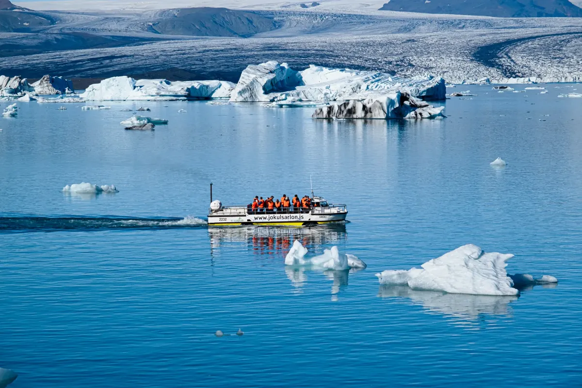 A scenic boat tour in a glacial lagoon surrounded by icebergs and serene waters.